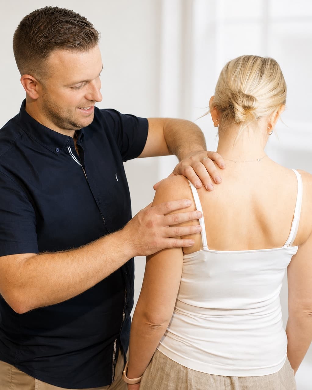 Matthew Yeates assessing a patient's shoulder during a consultation